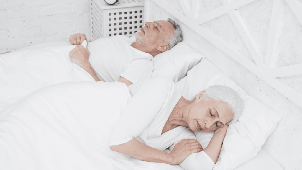 Pareja mayor durmiendo en colchón blanco